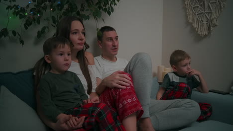 Family-Bonding-at-Christmas.-together-on-a-sofa-and-watching-TV-at-home-during-Christmas-holidays.-High-quality-4k-footage